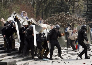 Policejní těžkooděnci pod palbou kamenů a cihel.